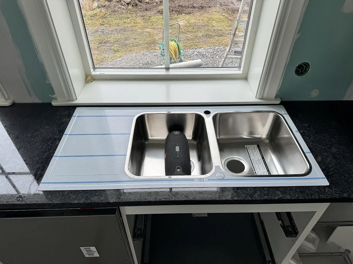 Dubbel diskho i rostfritt stål monterad ovanpå en polerad Steel Grey granitbänkskiva i Älmestad.