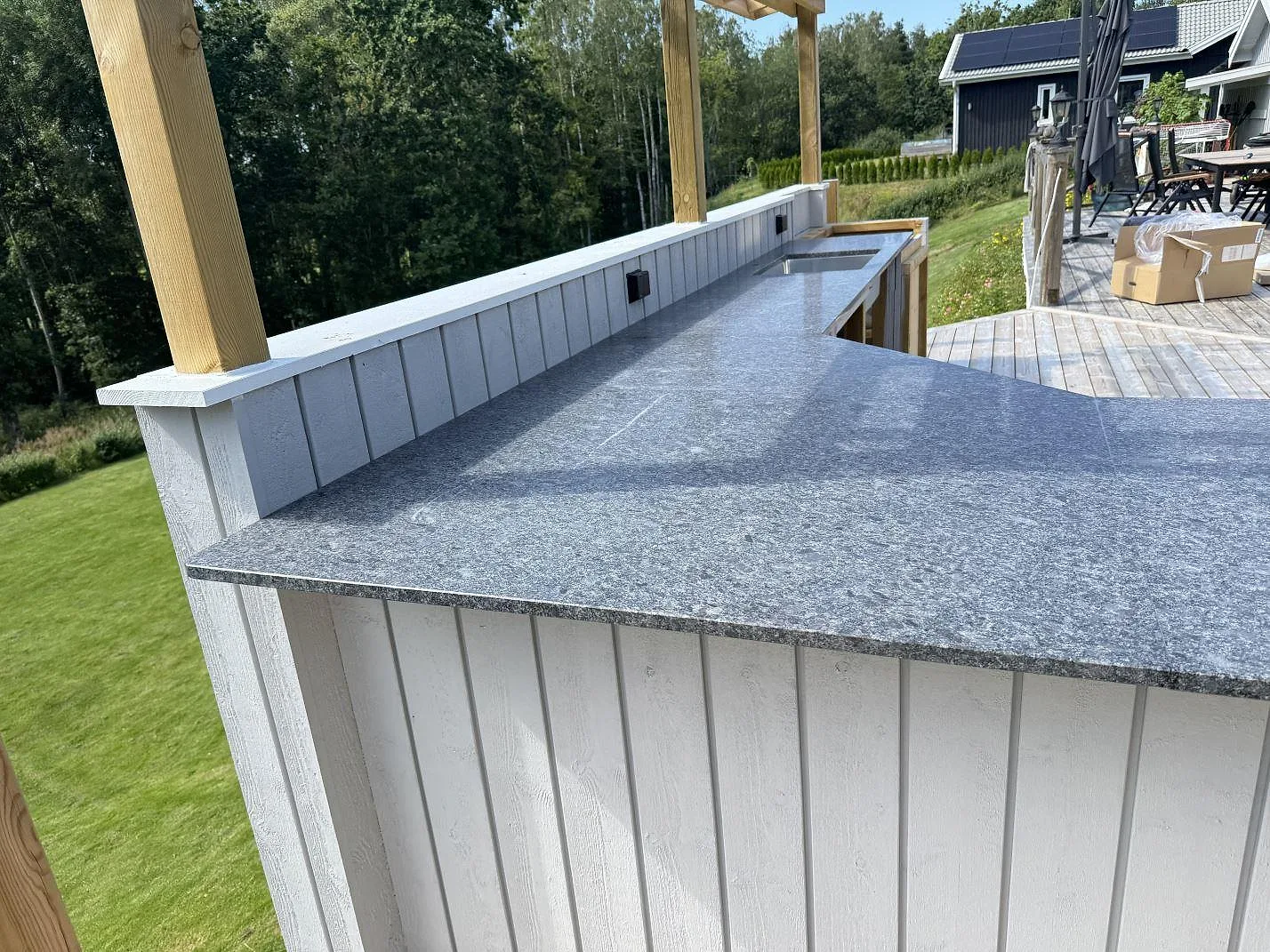 Köksbänkskiva i matt Steel Grey granit i Fjärås, monterad runt ett utekök med synlig bakre stenkant.