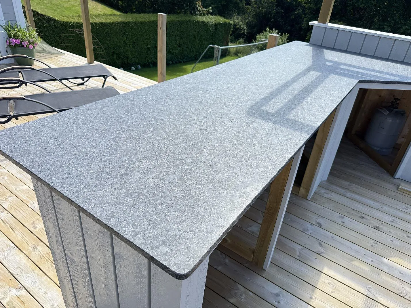 Vinklad arbetsyta i matt Steel Grey granit för utekök i Fjärås, monterad över trästommar.