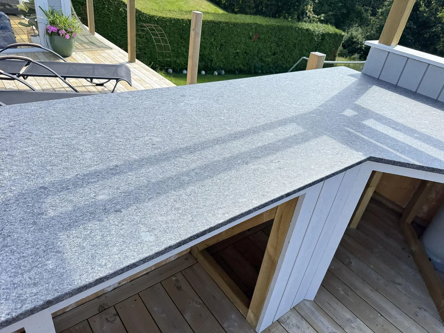 Detalj av hörn och skarv i matt Steel Grey granit på en köksbänkskiva utomhus i Fjärås.