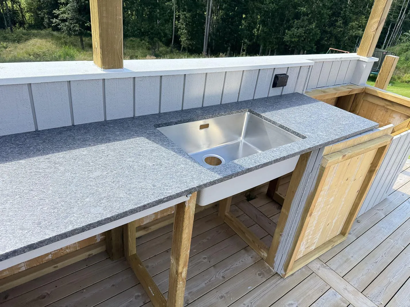 Rostfri diskho i en bänkskiva av matt Steel Grey granit i ett utekök i Fjärås.