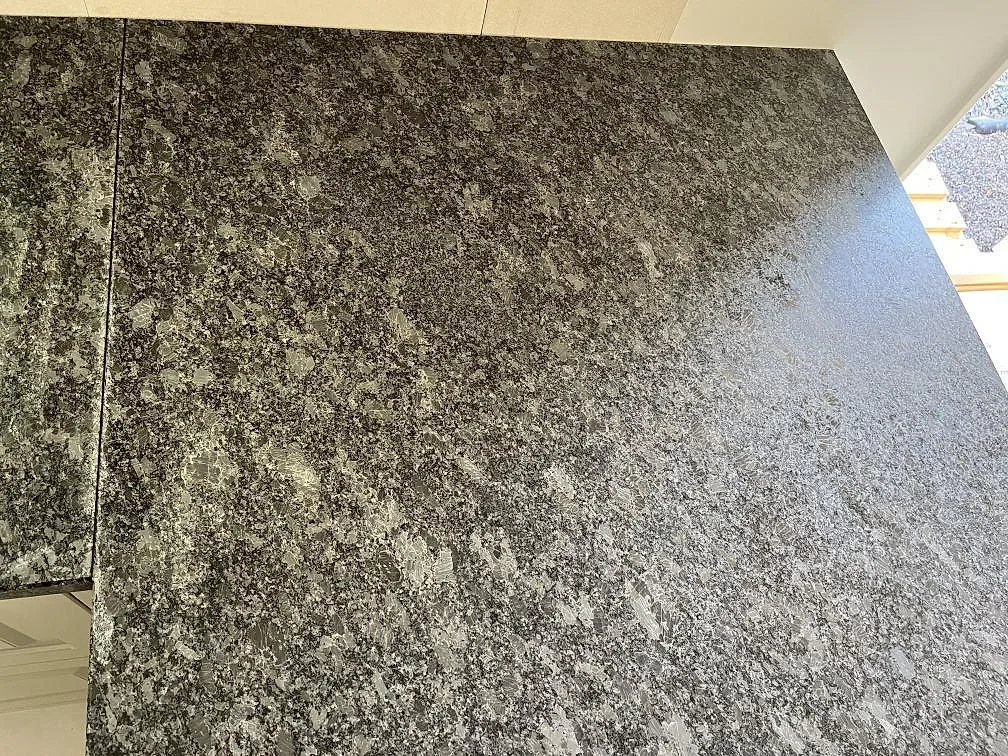 Närbild på matt Steel Grey granitbänkskiva med ljusa silvergrå korn och dagsljus från fönstret i ett kök i Frillesås.