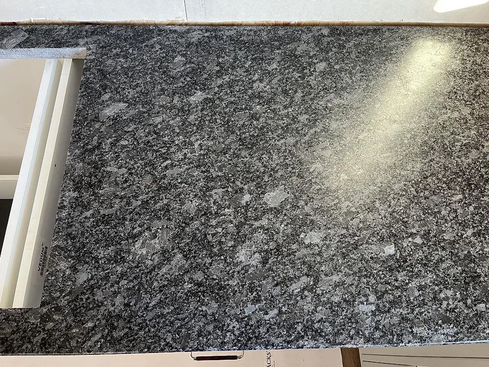 Steel Grey granitbänkskiva i matt yta mot vit köksstomme med mjuk ljusreflex i ett kök i Frillesås.