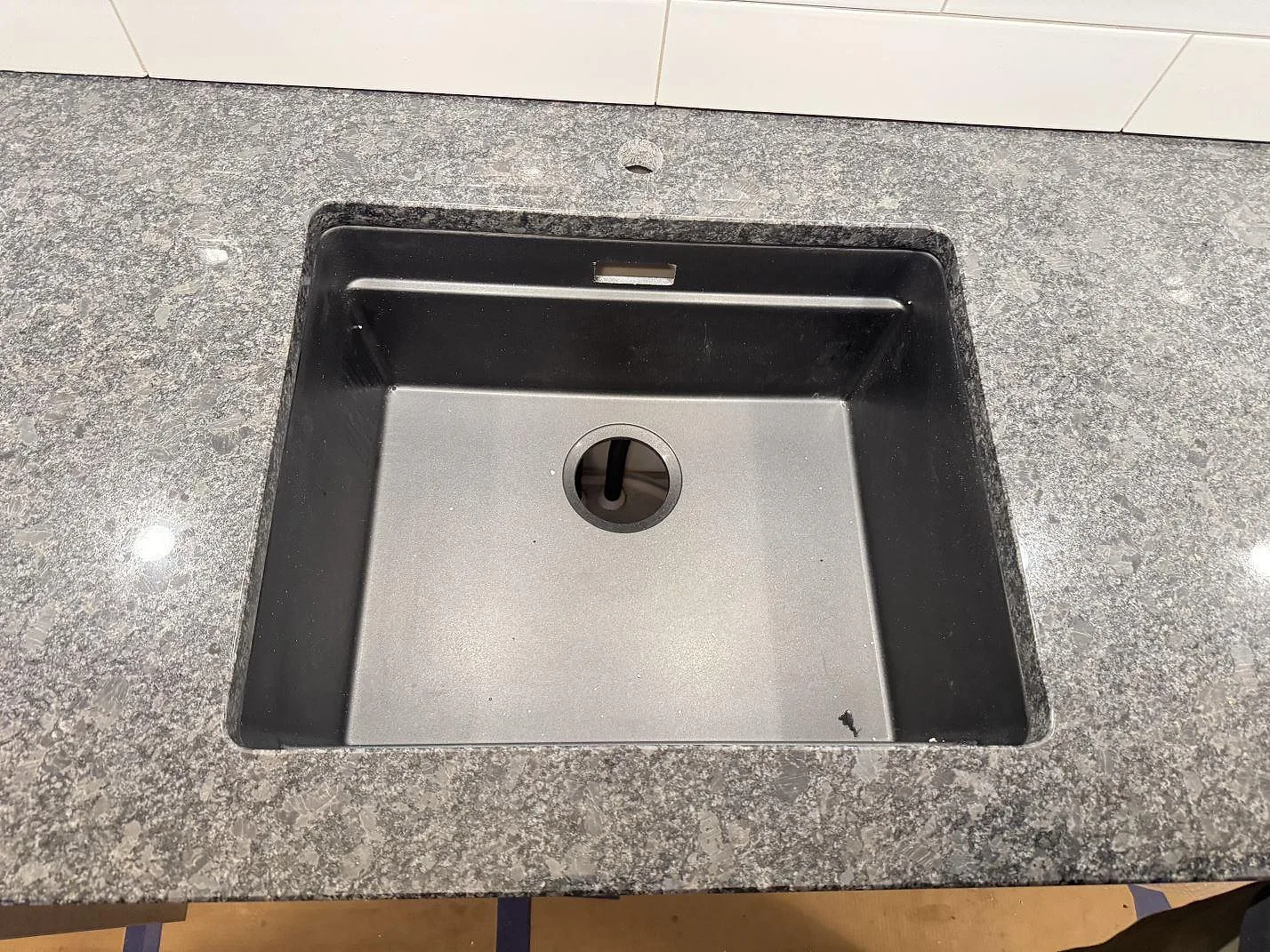 Närbild på diskho i polerad Steel Grey granit med grå kristallstruktur i ett kök i Glommen.