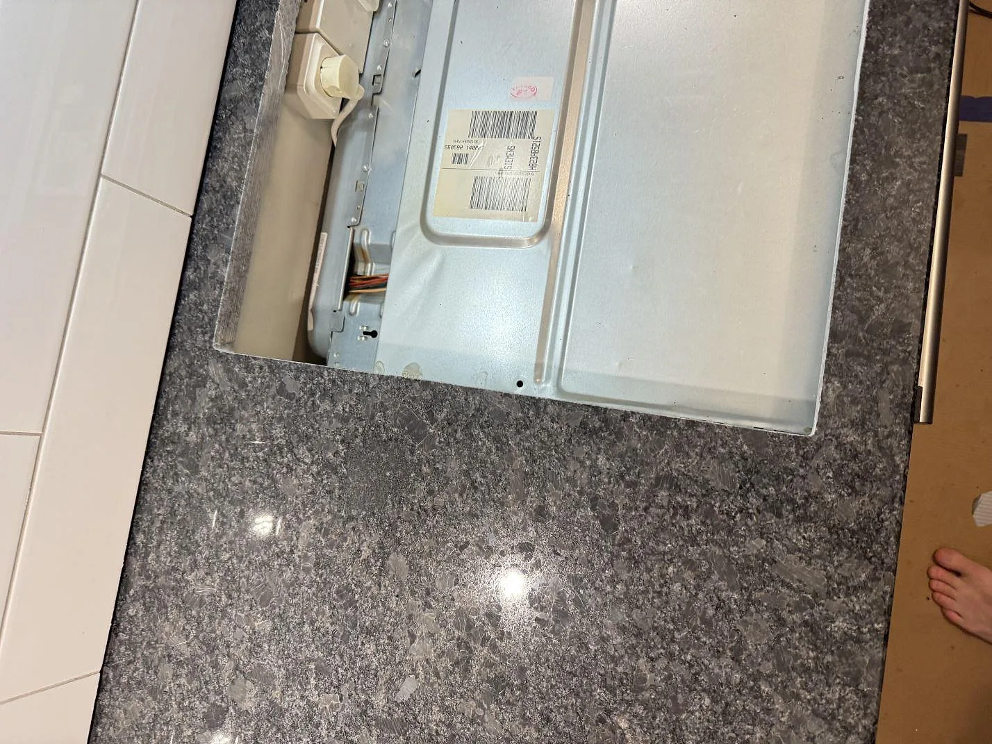 Detalj av polerad Steel Grey granit intill hällöppning och köksstomme under montering i Glommen.