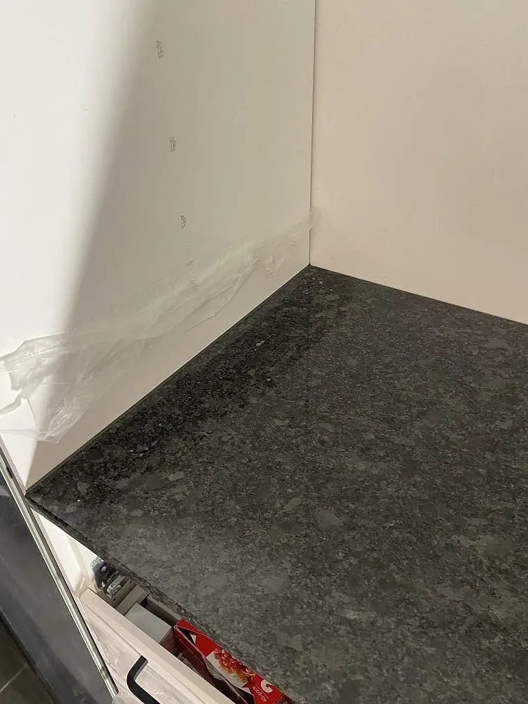 Matt Steel Grey-granitskiva med uppvikt stänkkant monterad mot vägg i ett kök i Göteborg, bild tagen innan rummet var helt inrett.