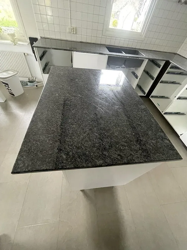 Köksö i polerad Steel Grey granit med markerad ådring i ett kök under montering i Halmstad.