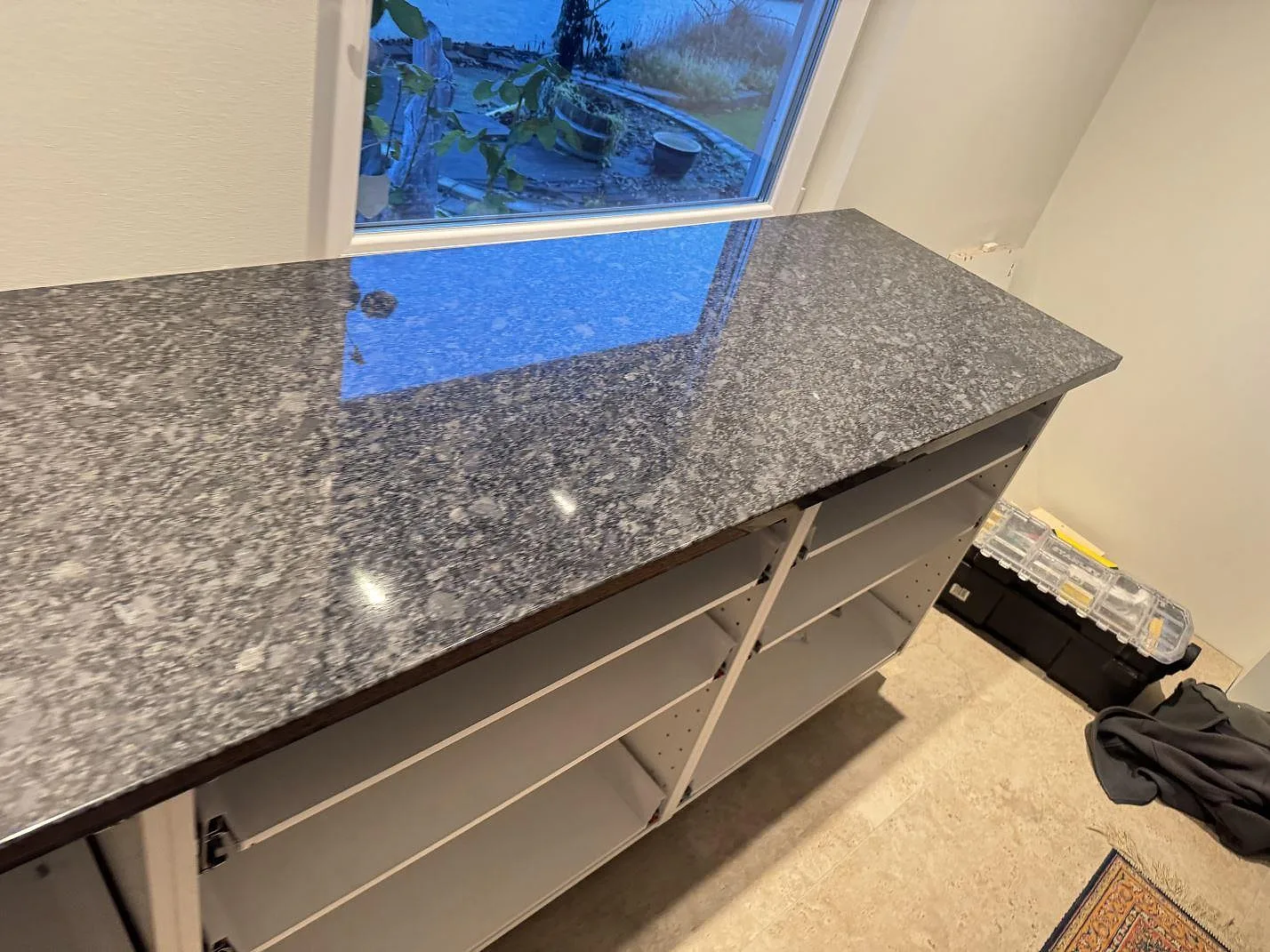 Polerad Steel Grey-granit som arbetsbänk vid fönster med synlig kristallstruktur under montering i Haverdal.