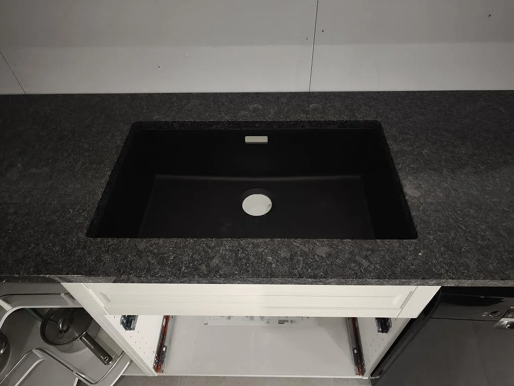Detalj av mörk diskho monterad i polerad köksbänkskiva av Steel Grey granit i Helsingborg.