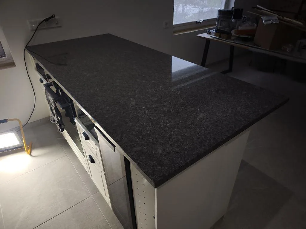 Polerad köksbänkskiva i Steel Grey granit med bred arbetsyta och halvö i ett kök under montering i Helsingborg.