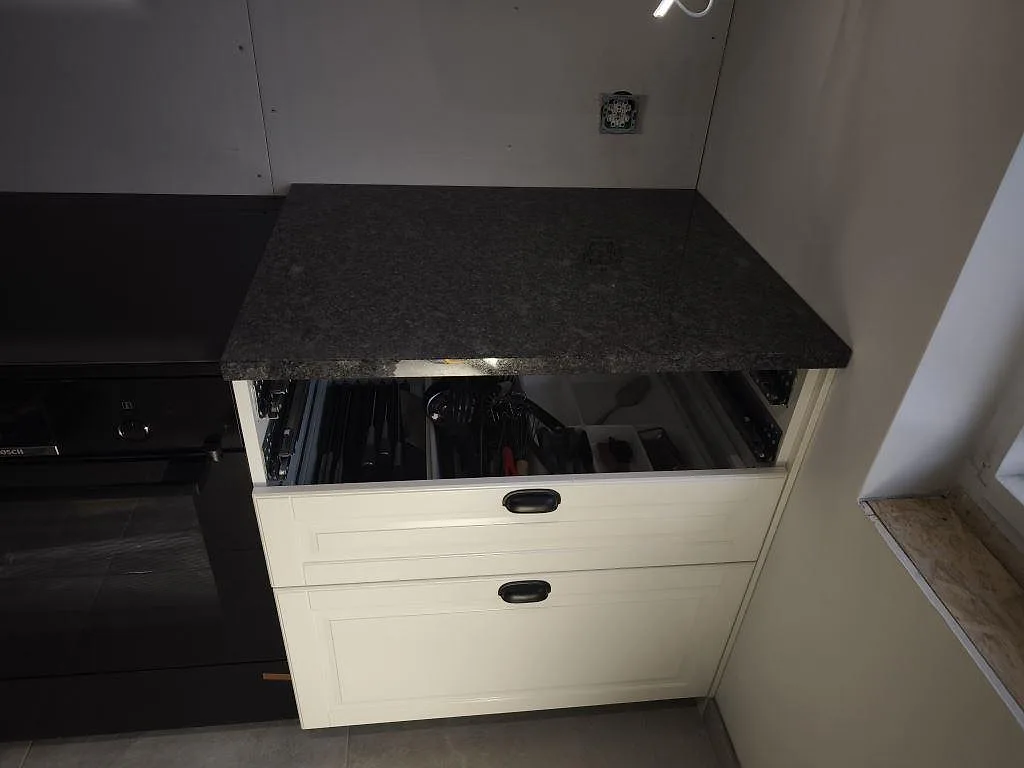 Kort köksbänkskiva i polerad Steel Grey granit vid fönster och lådhurts i ett kök i Helsingborg.