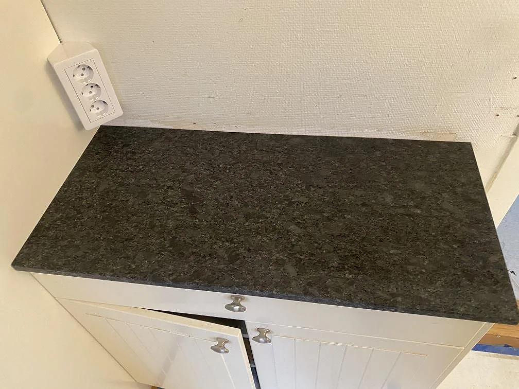 Köksbänkskiva i Steel Grey granit med matt yta och fin kornstruktur ovanpå vita köksskåp i Hindås.
