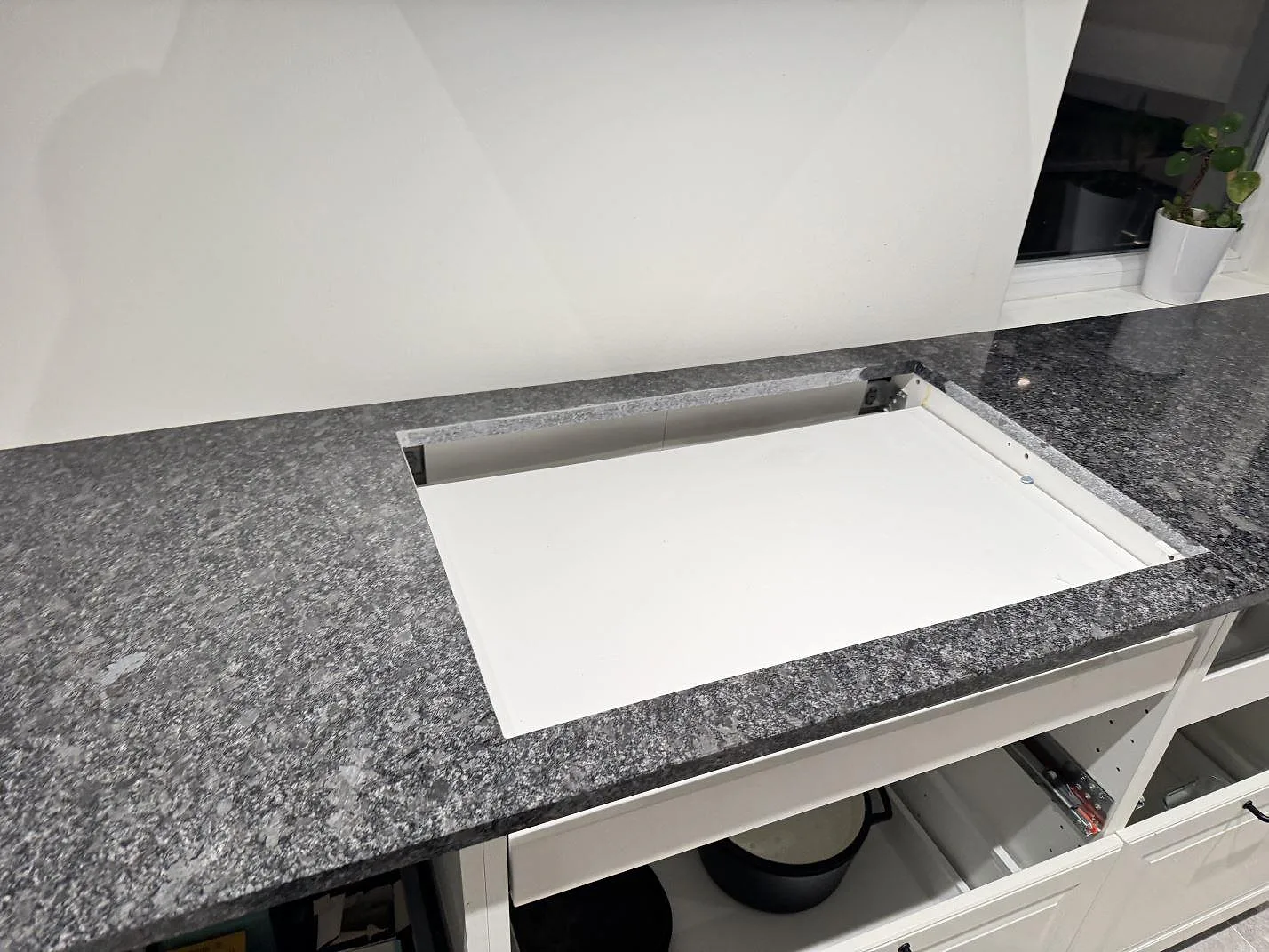 Köksbänkskiva i Steel Grey-granit med urtag och uppvikt stänkkant under montering i ett kök i Kävlinge.