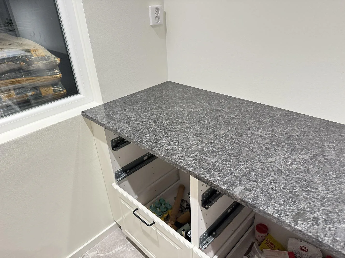 Polerad köksbänkskiva i Steel Grey-granit längs en bänkrad med spräcklig grå yta i ett kök i Kävlinge.