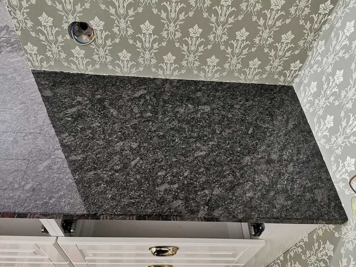 Ovanifrån av en köksbänkskiva i polerad Steel Grey granit med fin spräcklig grå ådring i ett kök i Knisslinge.