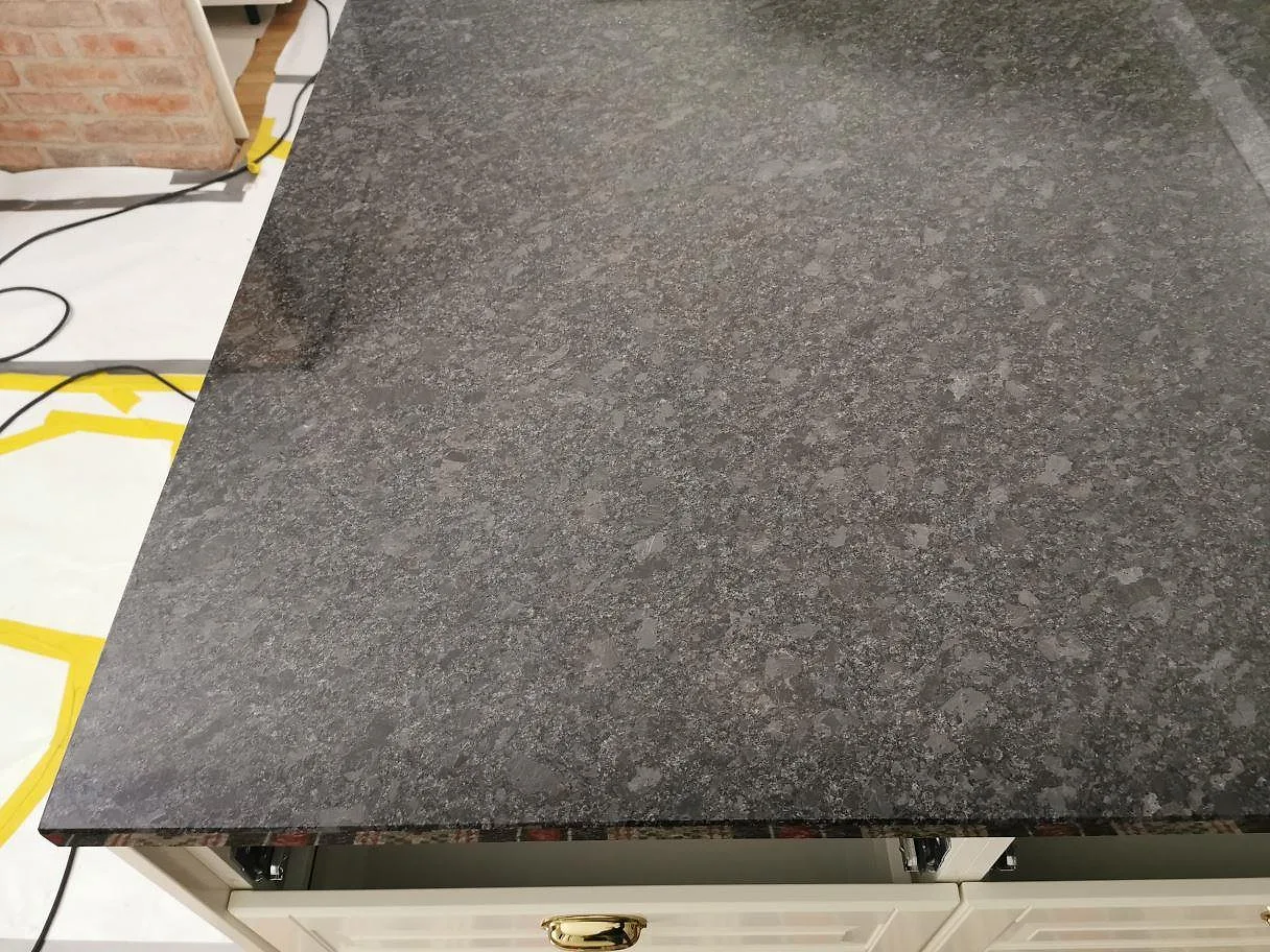 Detalj av kanten på en köksbänkskiva i polerad Steel Grey granit med rakfasad kant i ett kök i Knisslinge.