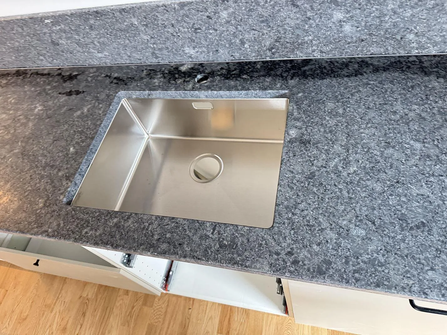 Närbild av Steel Grey granit med lädermatt yta runt en rostfri diskho i ett kök i Bjärred.