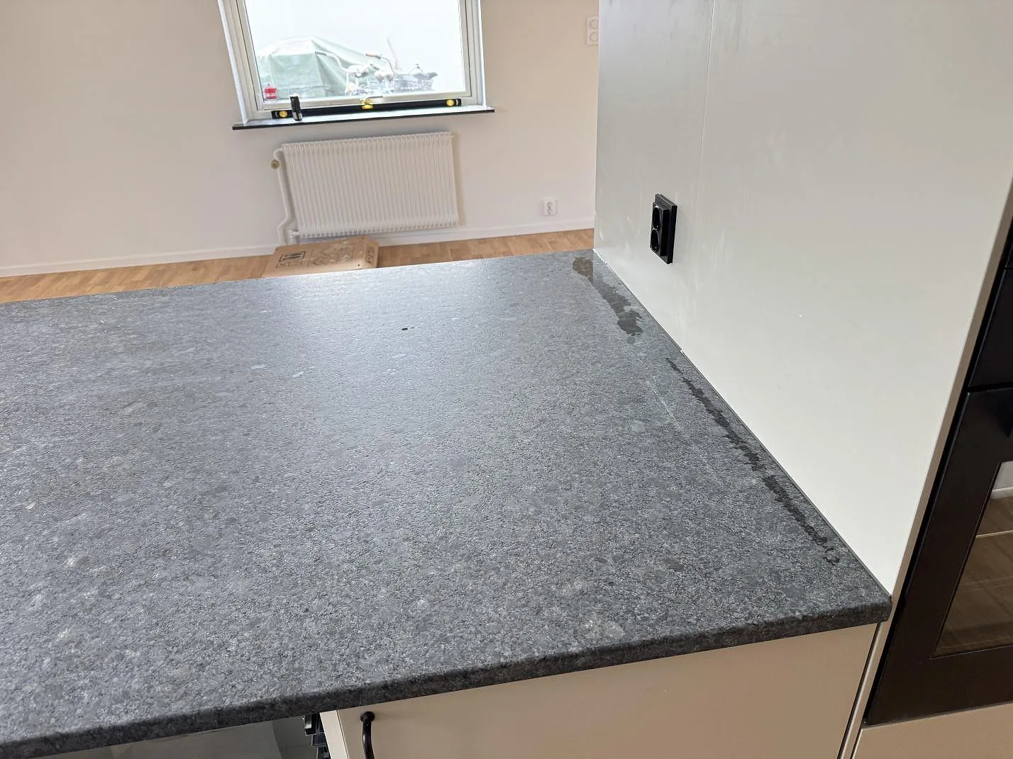 Närbild av den lädermatta ytan på Steel Grey granit som bänkskiva vid vägg och fönster i Bjärred.