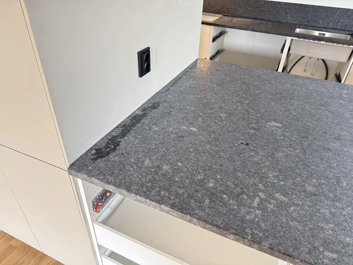 Bred arbetsyta i Steel Grey granit med lädermatt finish framför köksbänken under montering i Bjärred.