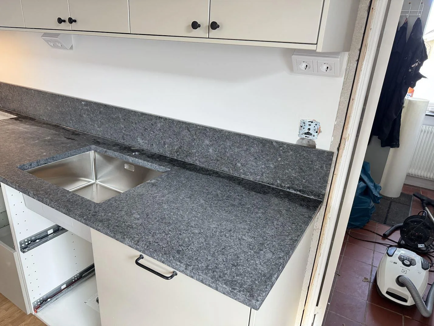 Köksbänkskiva i Steel Grey granit med lädermatt yta, rostfri diskho och stänkkant under montering i Bjärred.