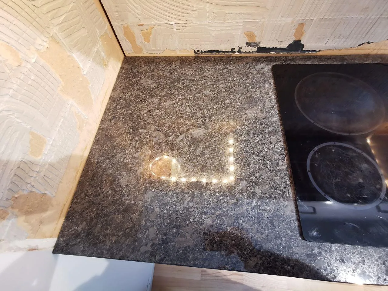 Hörn av den polerade Steel Grey-granitbänkskivan vid spishällen i ett kök i Lindome.