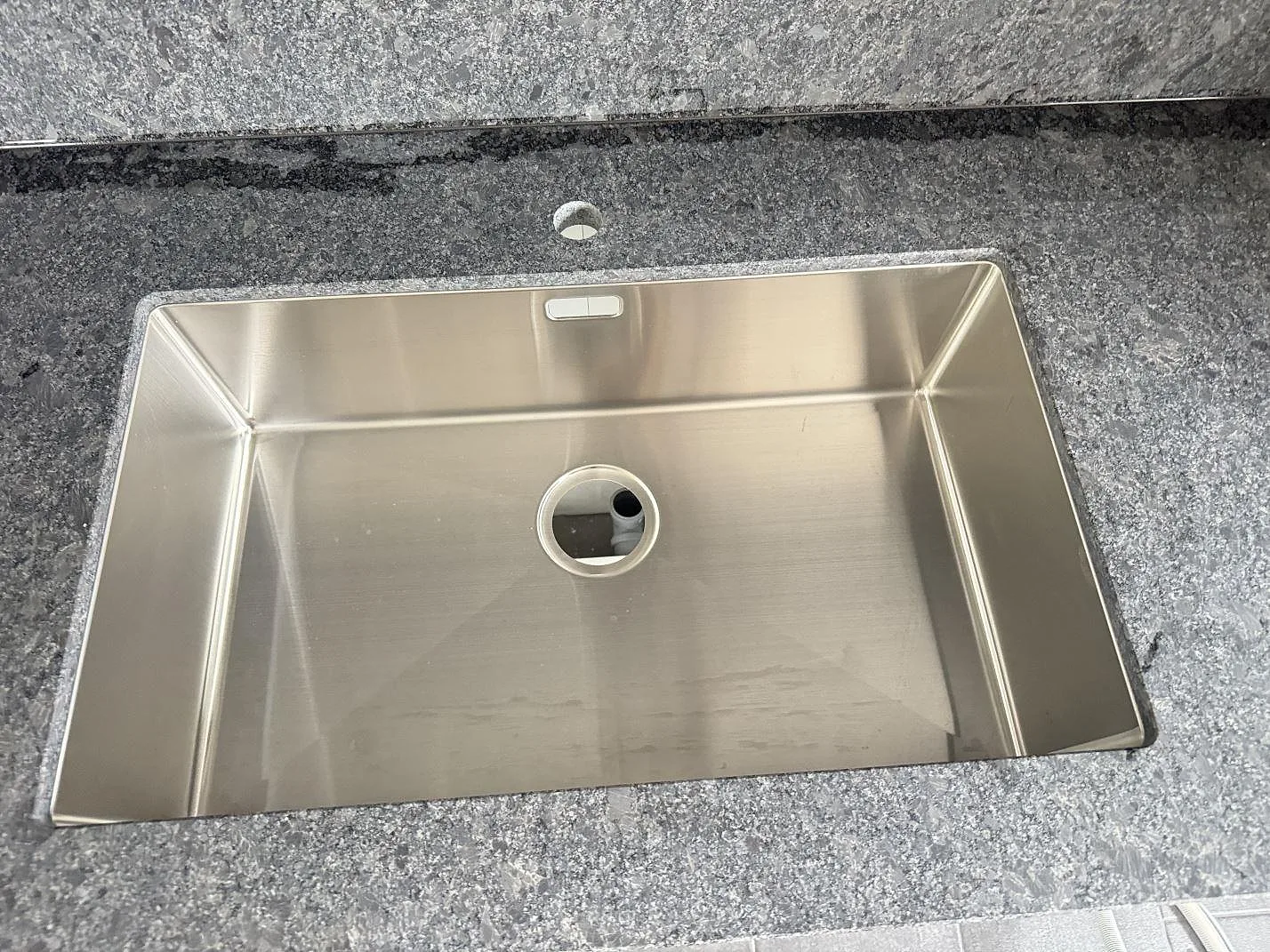 Närbild på rostfri diskho monterad i en matt Steel Grey granitskiva i köket i Löberöd.
