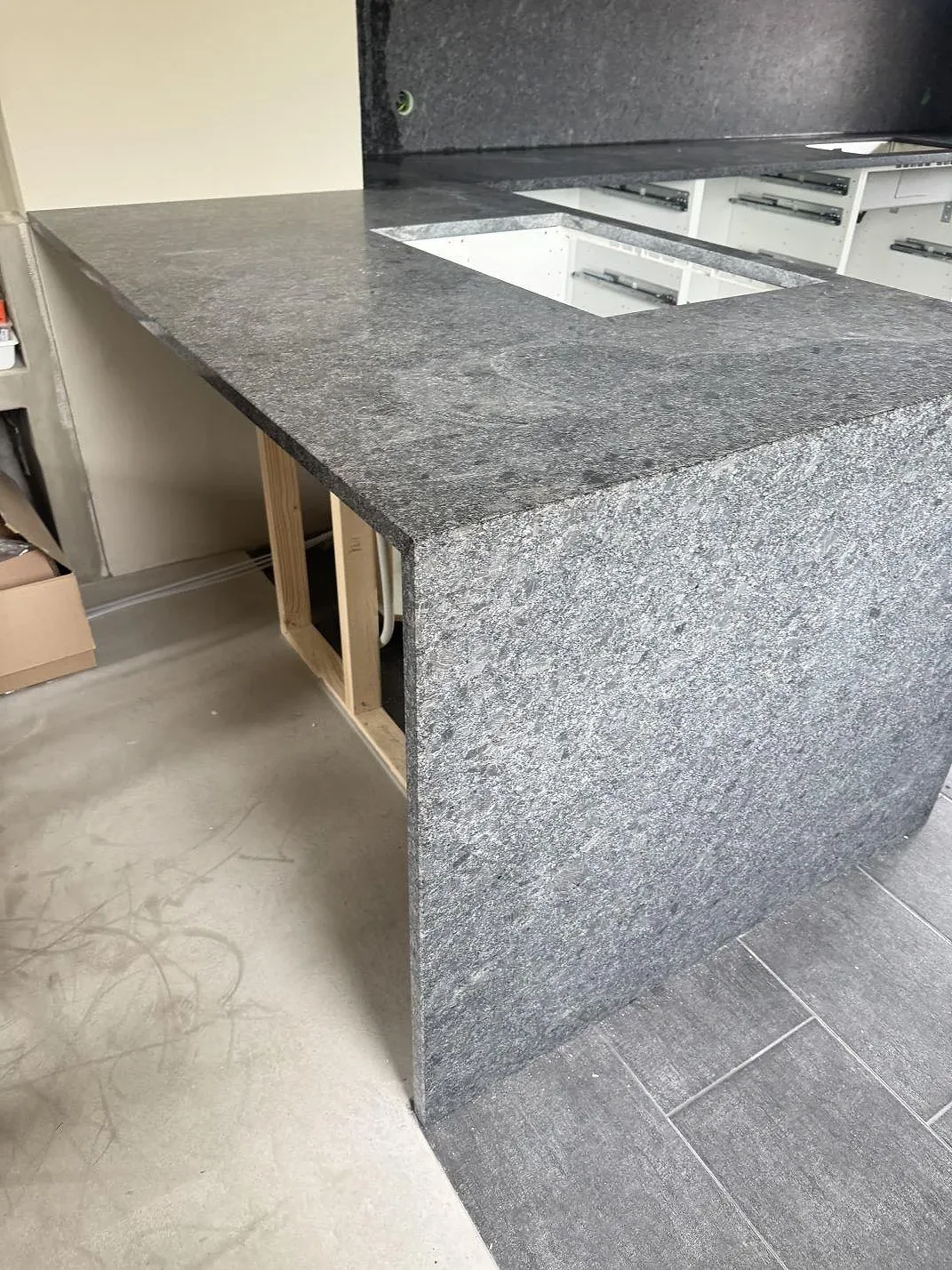 Stenklädd gavelsida och bänkyta i matt Steel Grey granit med urtag i köket i Löberöd.