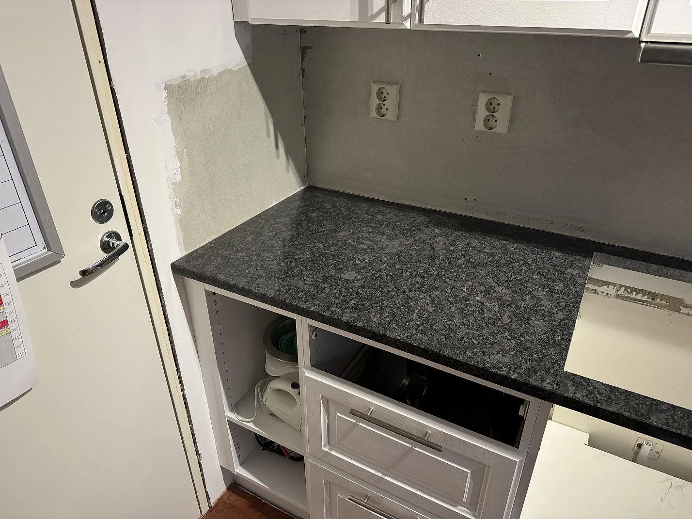 Vänster del av köksbänkskiva i polerad Steel Grey granit med öppen stomme och väggarbete i Lund.
