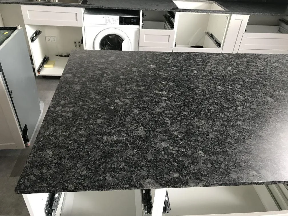 Topp av köksö i Steel Grey granit med tydlig kornig ådring i ett kök i Malmö.