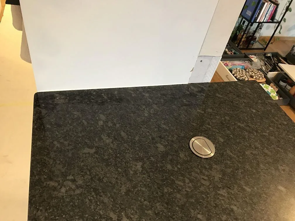 Bänkskiva i Steel Grey granit med rund kabelgenomföring i borstat stål i ett kök i Malmö.