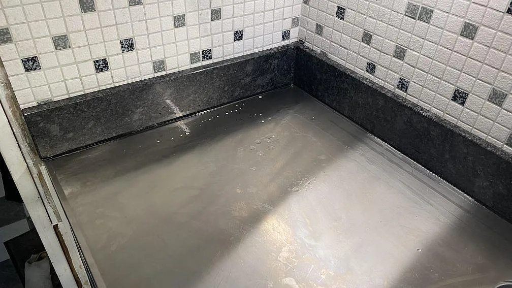 Polerad Steel Grey granitbänk med uppvikt stänkkant mot vägg i ett kök i Mölndal.