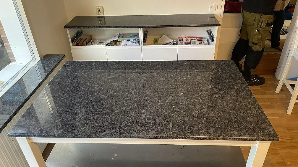 Polerad Steel Grey granitbänk med köksö och uppvikt stänkkant i ett kök i Mölndal.