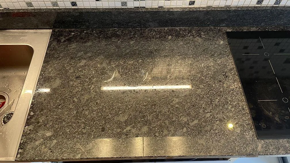 Närbild på polerad Steel Grey granitbänk med underlimmad rostfri diskho i ett kök i Mölndal.