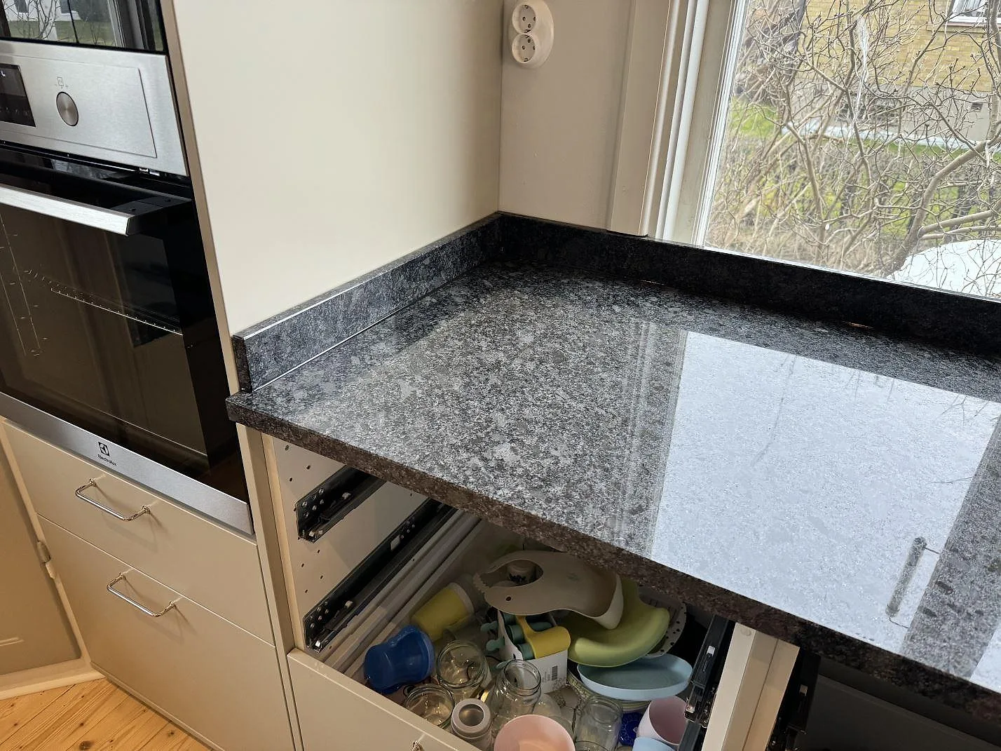 Köksbänkskiva i Steel Grey-granit vid inbyggnadsugn och fönster, fotograferad under montering i Mölndal.