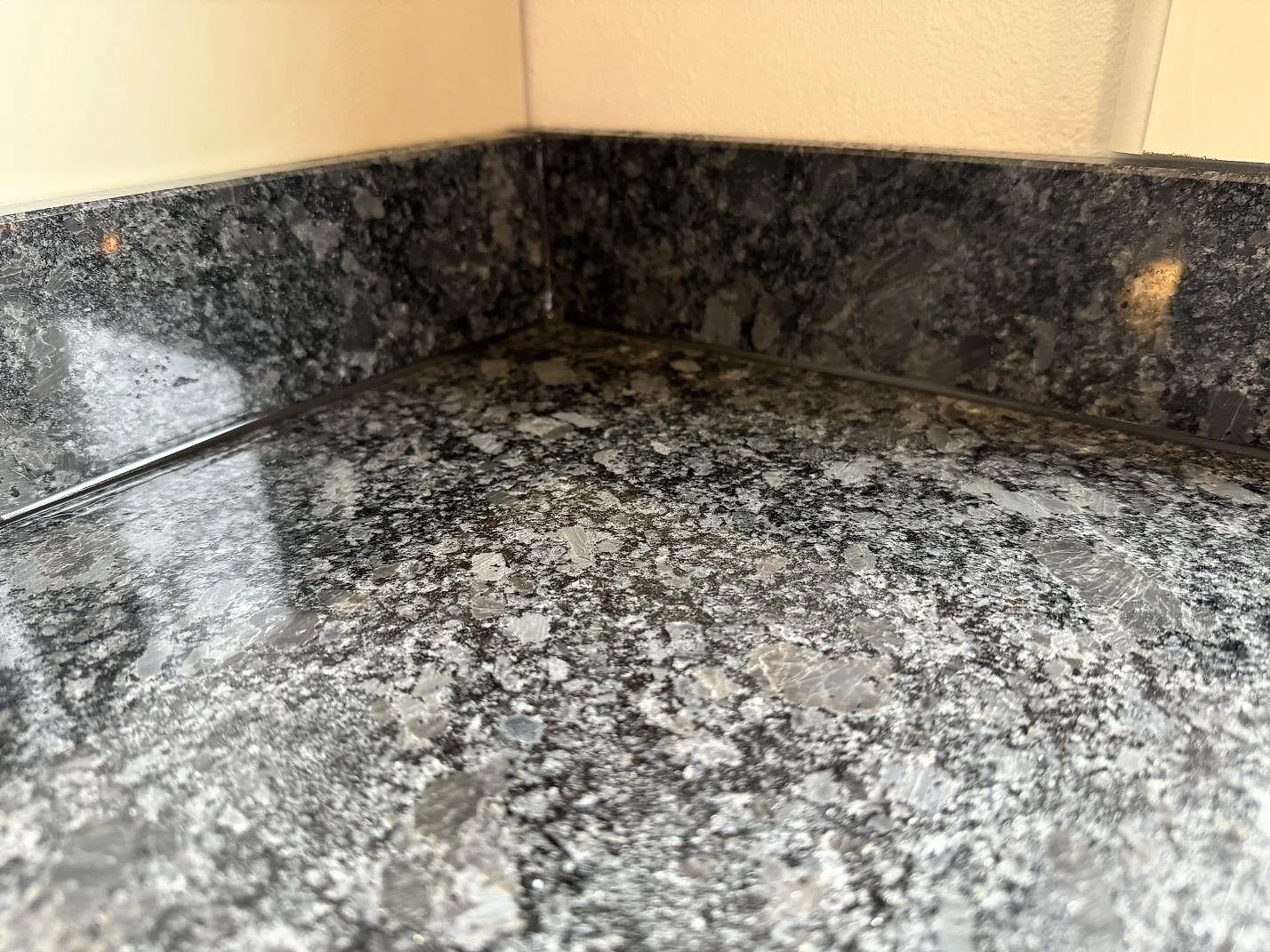 Närbild på hörn och uppvikt stenkant i polerad Steel Grey-granit under montering i Mölndal.