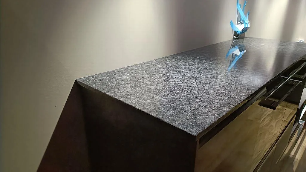 Närbild av polerad Steel Grey granit på köksbänk med blank yta och grå flammig struktur i Nybro.