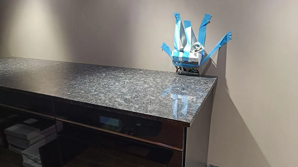 Sidovy av polerad Steel Grey granit som bänkskiva på mörka köksstommar under montering i Nybro.