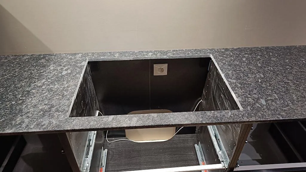 Detalj av rektangulär öppning i 20 mm polerad Steel Grey granit på köksbänk under montering i Nybro.