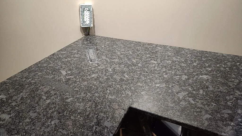 Närbild av hörn och yta i polerad Steel Grey granit på installerad köksbänkskiva i Nybro.