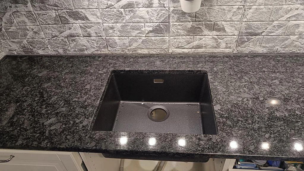 Underlimmad mörk diskho monterad i köksbänkskiva av polerad Steel Grey granit i Oxie.