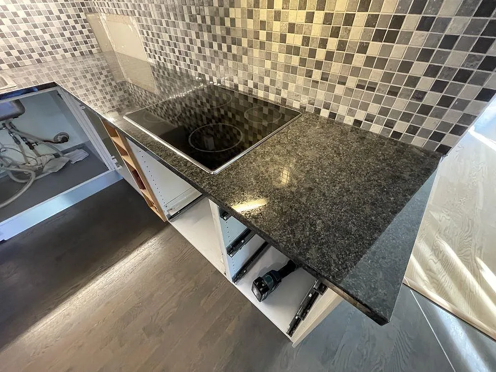 Detalj av polerad Steel Grey granit som köksbänkskiva med häll och blank stenstruktur i Saltsjö boo.