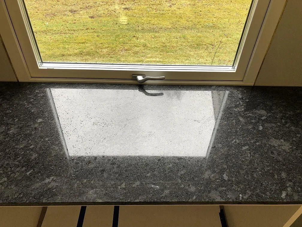 Fönsterbänk i Steel Grey granit monterad vid ett fönster i ett kök i Södra Rörum.