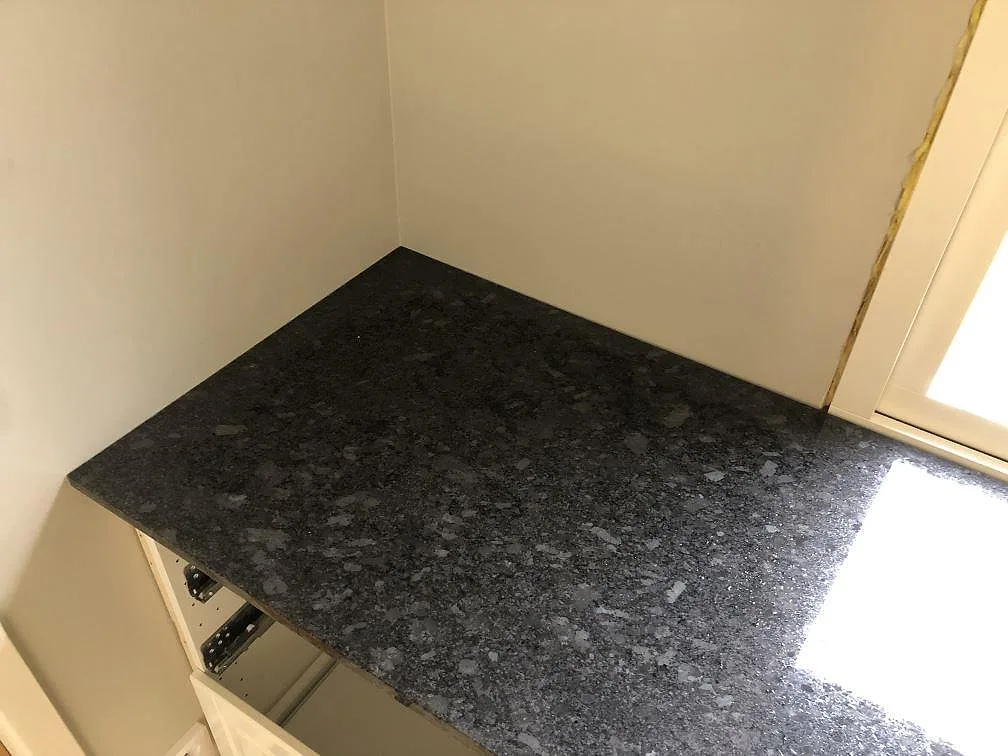 Eye-level bild av en köksbänkskiva i Steel Grey granit monterad i en hörnsektion i ett kök i Södra Rörum.