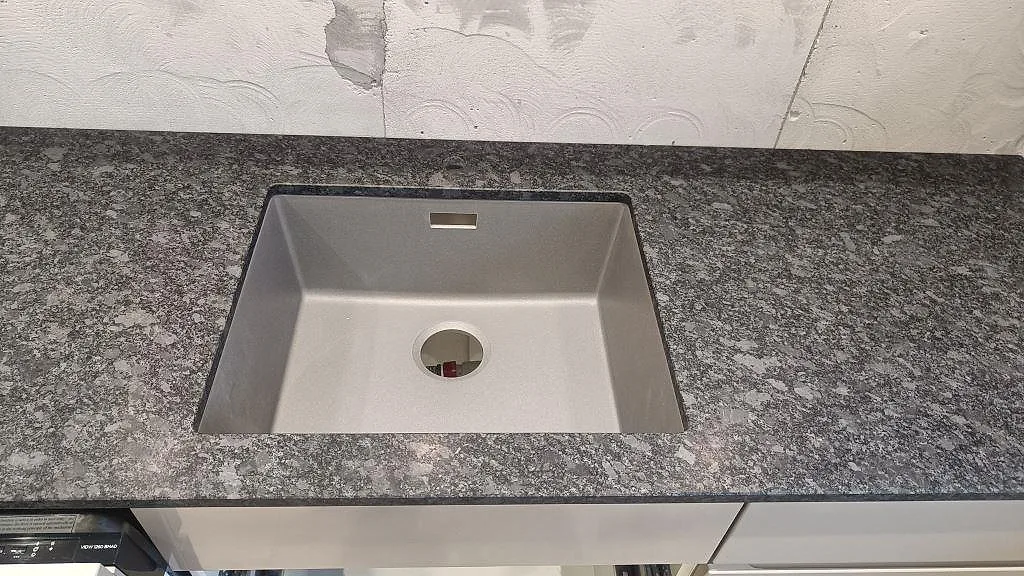Underlimmad diskho i en matt Steel Grey granitbänkskiva i ett kök i Staffanstorp.
