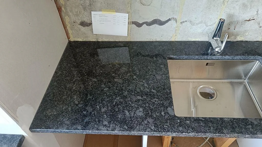 Polerad Steel Grey bänkskiva med underlimmad rostfri diskho och separat kranhål för köksblandaren i ett kök i Staffanstorp.