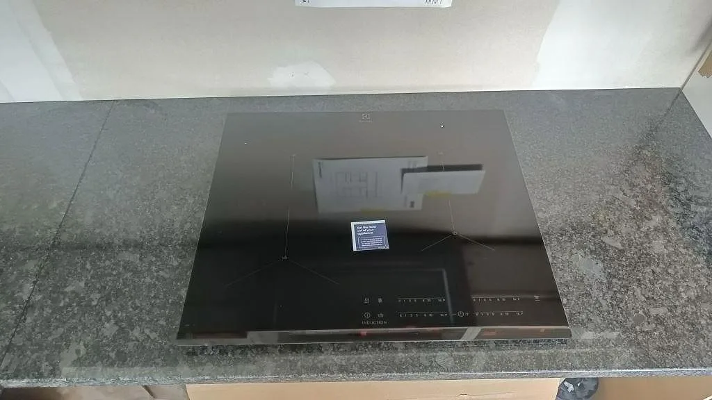 Köksbänkskiva i Steel Grey granit med infälld induktionshäll, polerad yta, i ett kök i Staffanstorp.