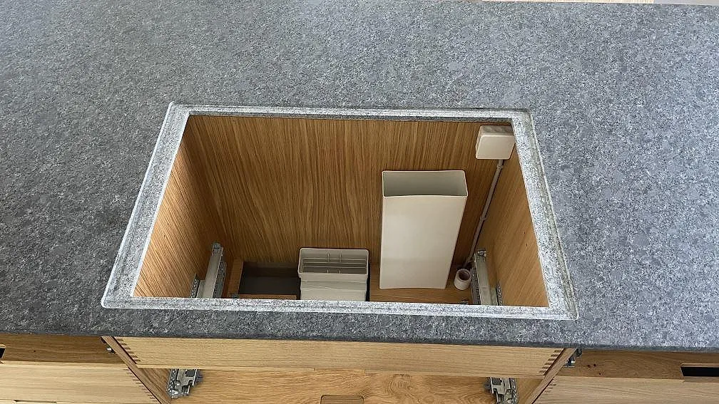 Detalj av förberedd öppning i köksö med matt Steel Grey granit och trästommar i köket i Stege.