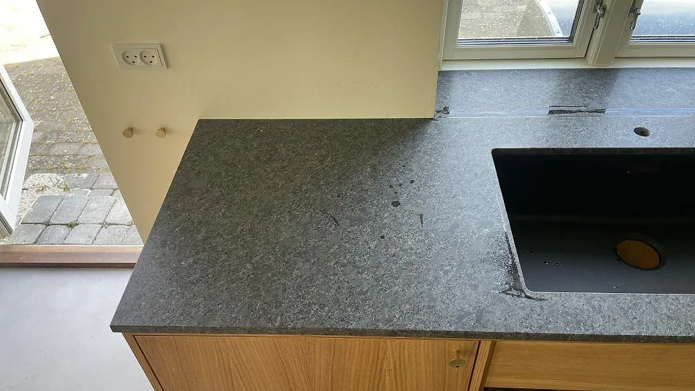 Matt Steel Grey granit på väggbänk med svart diskho och blandarhål vid fönster i ett kök i Stege.