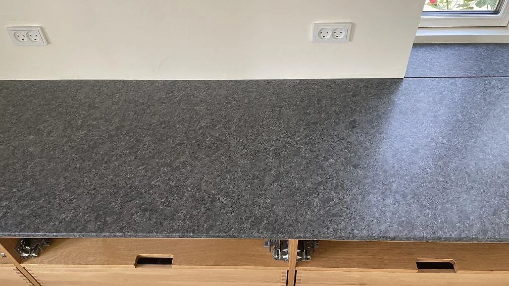 Ytbild av matt Steel Grey granit med mörkgrå kornstruktur på väggbänk under fönster i Stege.