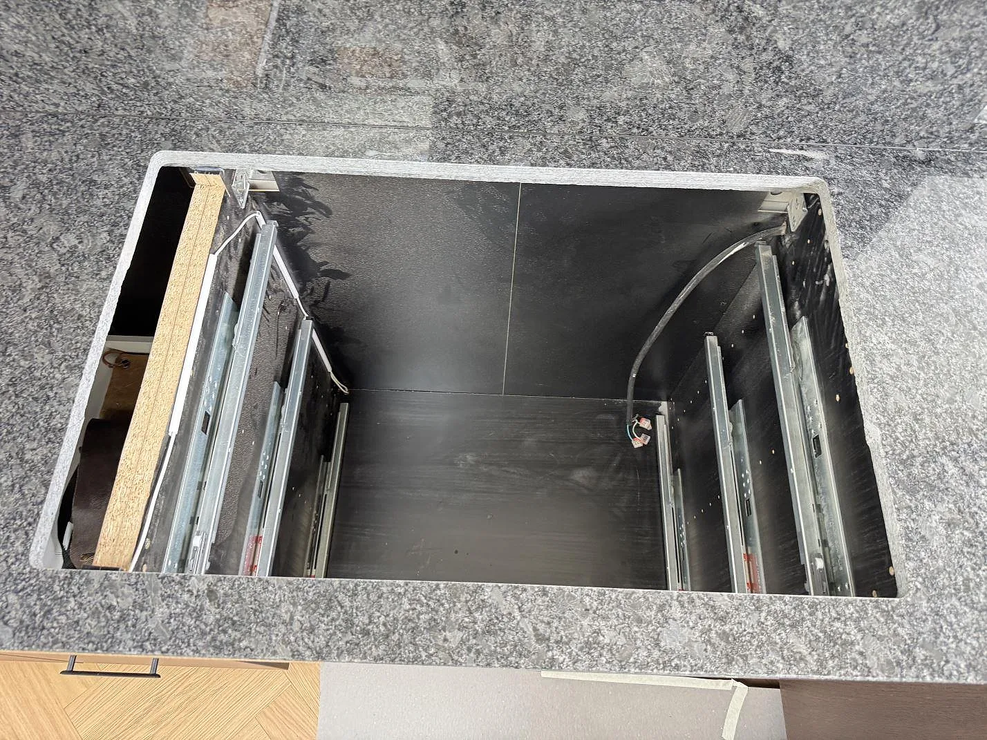 Öppet hällurtag i en polerad Steel Grey granitbänkskiva under montering i ett kök i Tølløse.